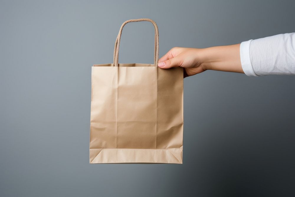A hand from the right side holds a package pouch Putting it into a shopping bag is held by a hand from the left side handbag…