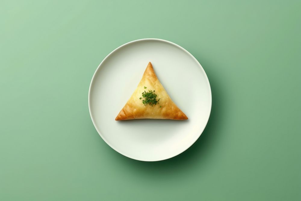 Samosas on a white plate green food green background.