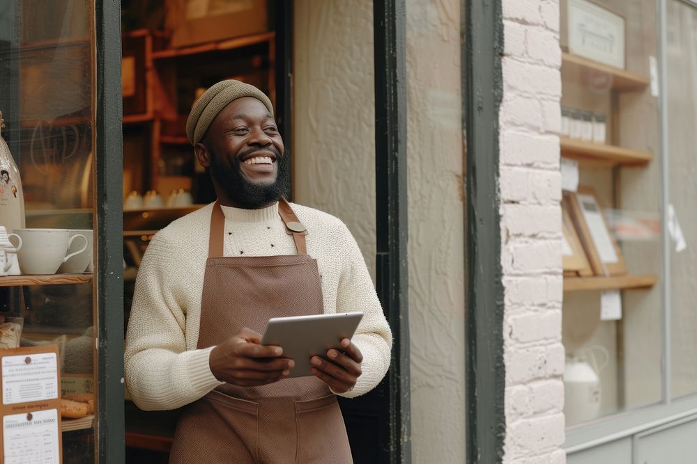 Black man holding tablet and standing at doorway of her coffee shop adult entrepreneur architecture.