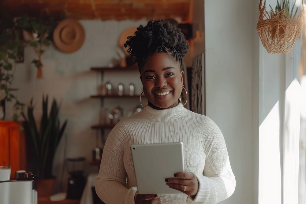 Black woman holding tablet and standing at doorway of her coffee shop smile happy entrepreneur.
