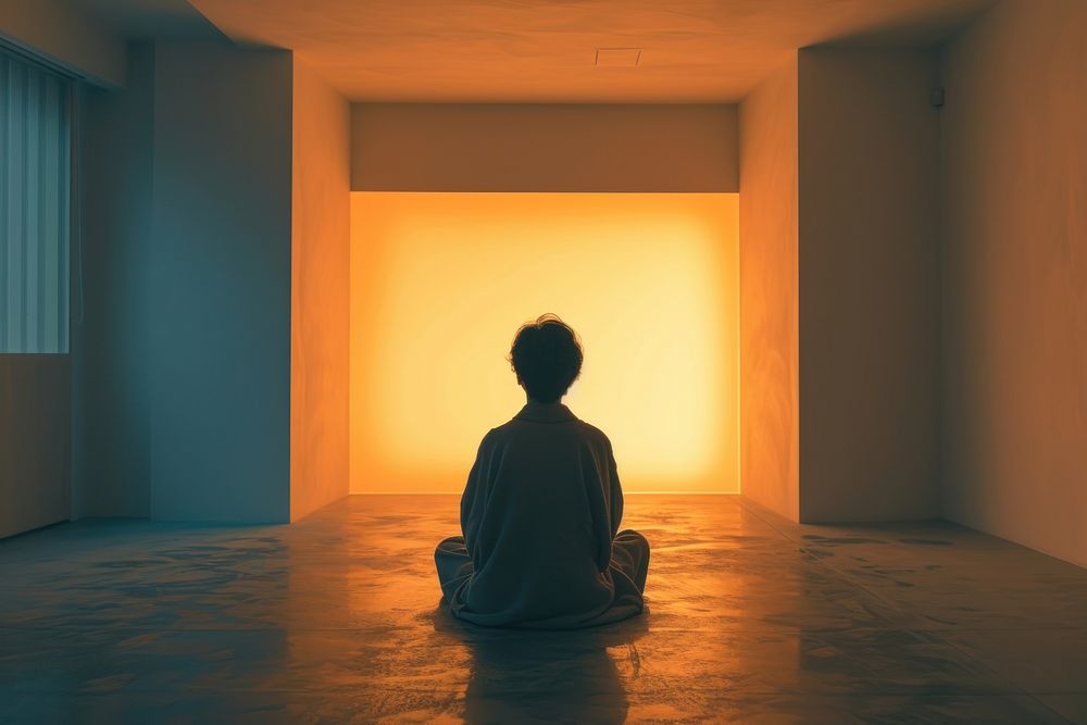 A person in a robe sitting in a room light adult contemplation.