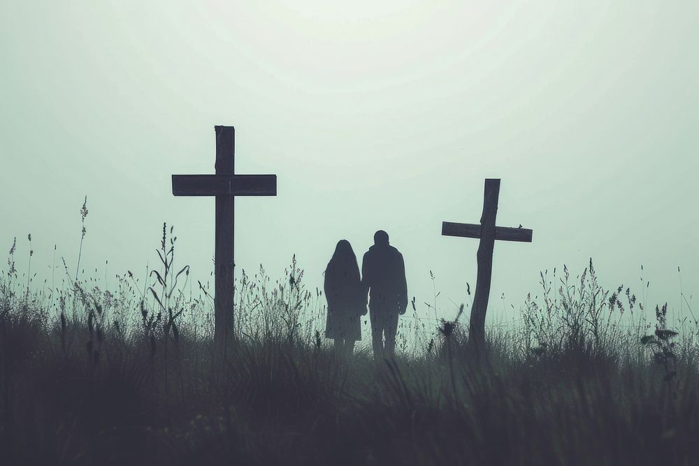 Couple silhouette at surreal wood crosses outdoors cemetery symbol.