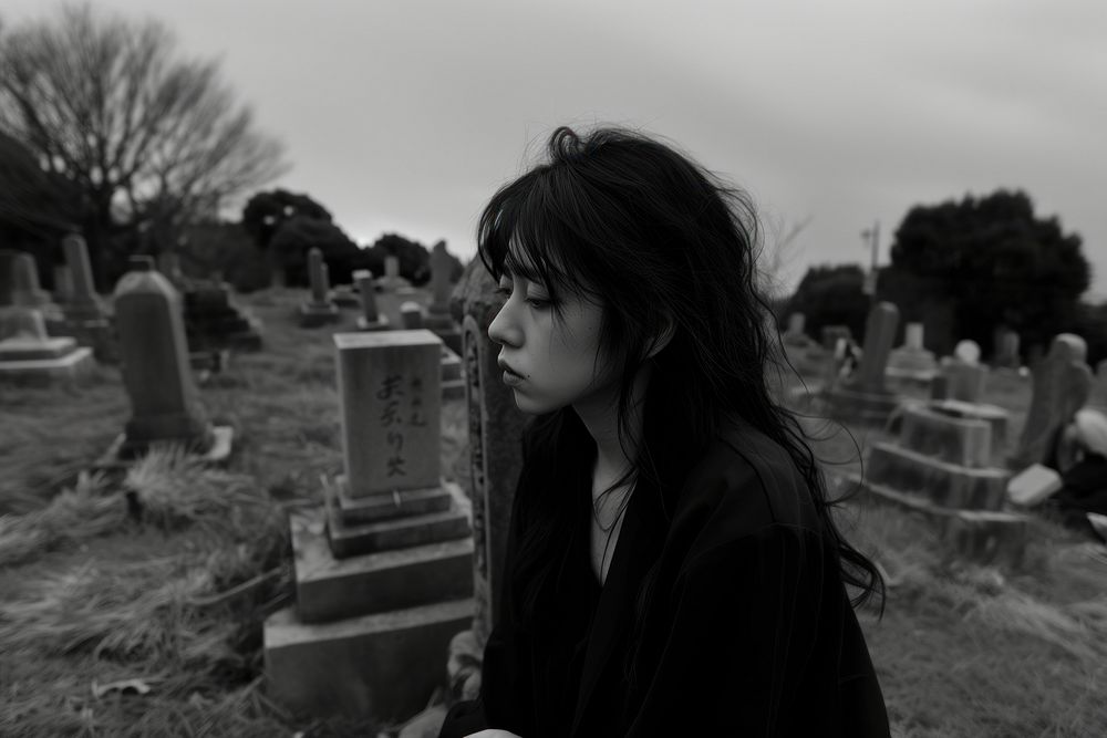 JapaneseYoung female crying at the grave tombstone cemetery outdoors.