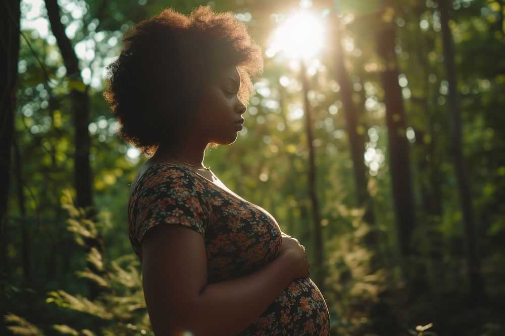 Black woman pregnant portrait outdoors woodland.