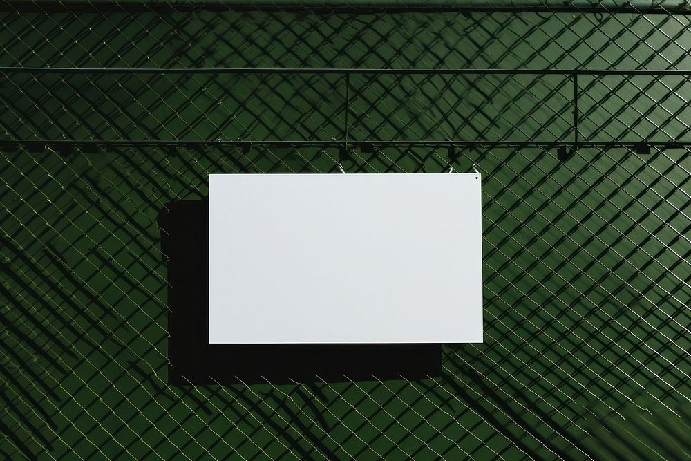A business card is hanging on a black grid fence green white wall.