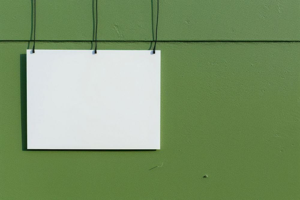 A business card is hanging on a black grid fence wall architecture green.