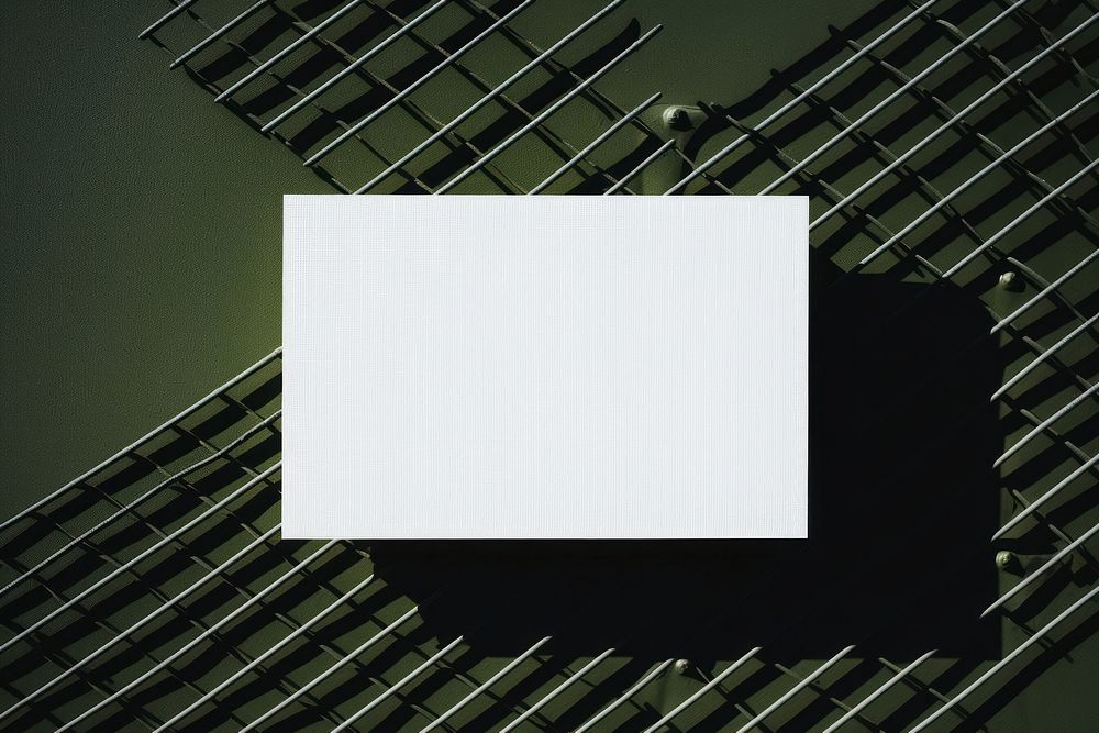 A business card is hanging on a black grid fence white green backgrounds.