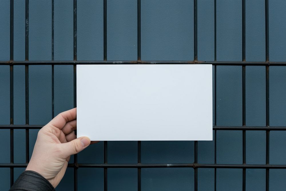 A business card is hanging on a black grid fence white paper blue.