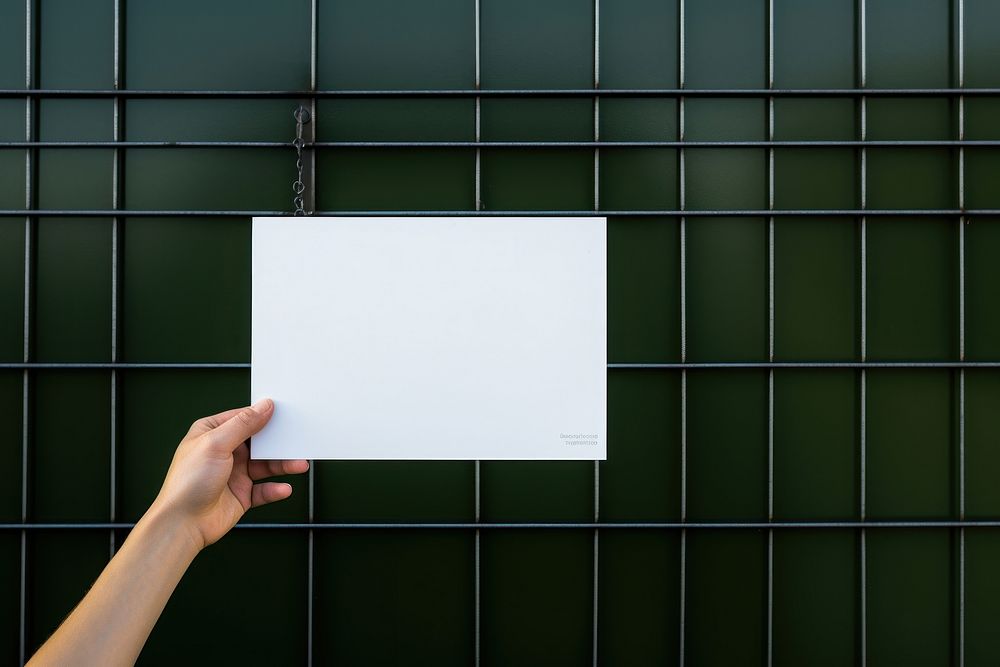 A business card is hanging on a black grid fence green wall holding.