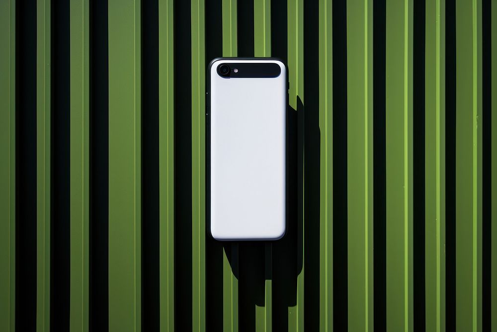 A smartphone on a black grid fence green electronics technology.