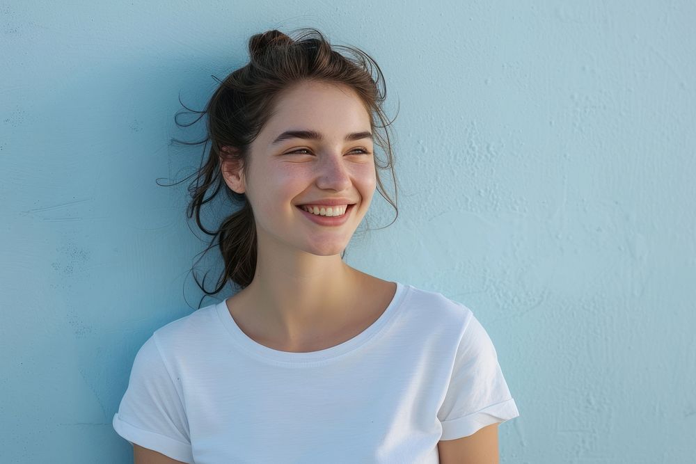 A happy woman wearing white t shirt smile blue wall.