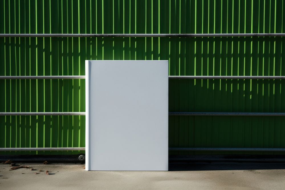 A white book is on a black grid fence green wall architecture.