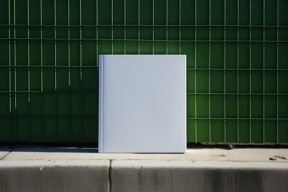 A white book is on a black grid fence wall architecture refrigerator.