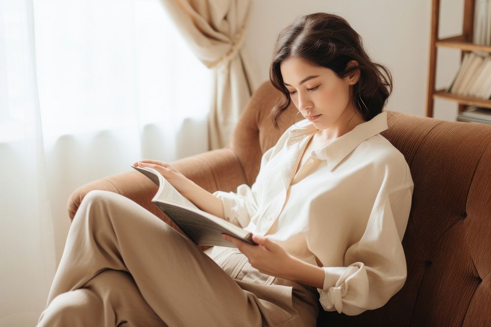 Woman laying on a couch and reading a book sitting adult contemplation.