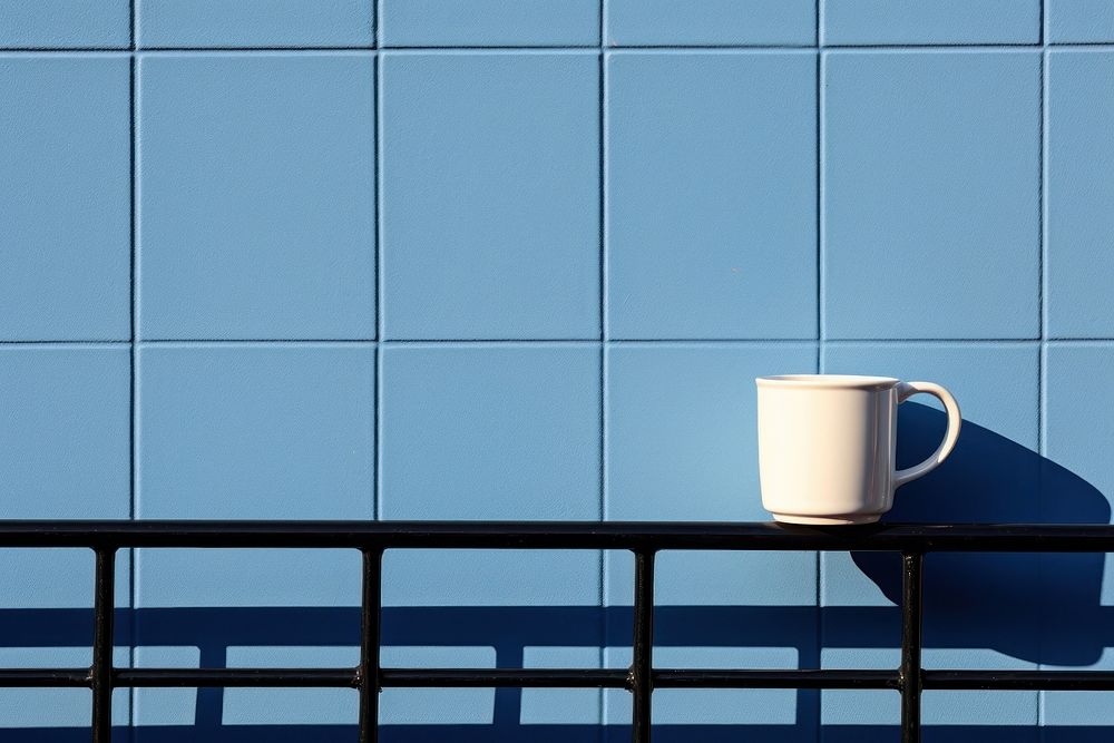 A coffee cup is on a black grid fence wall architecture drink.
