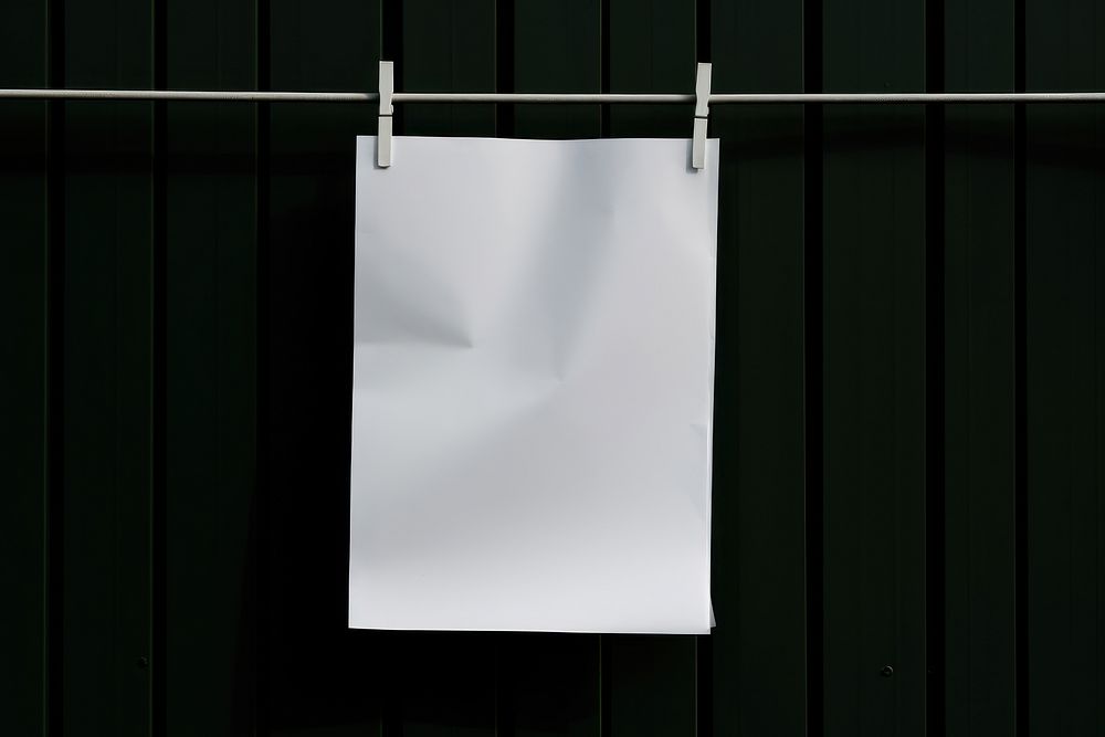 A paper is hanging on a black grid fence white green text.