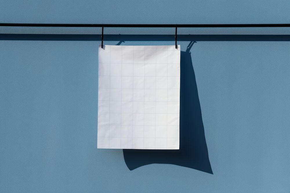 A paper is hanging on a black grid fence white blue wall.