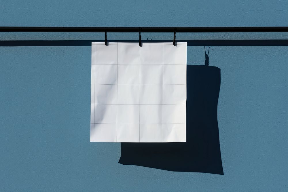 A paper is hanging on a black grid fence white blue wall.