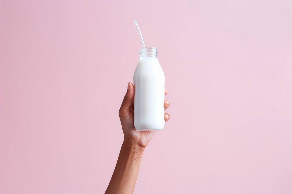 Hand holding a white milk bottle dairy refreshment container.