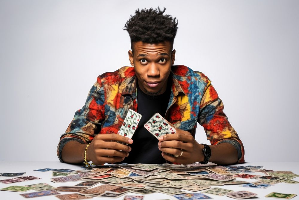 Black man in a patterned shirt gambling cards hand.