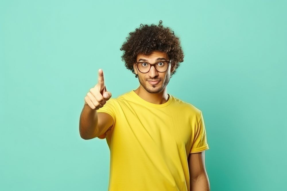 Indian man with curly hair glasses pointing standing.