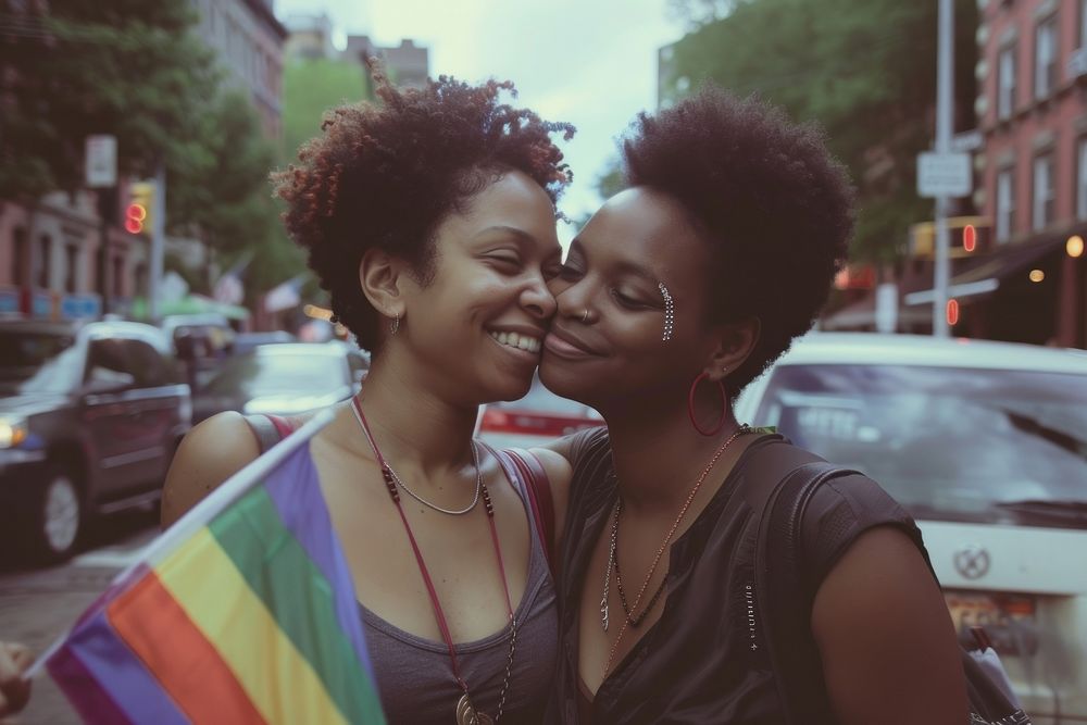 Black couple lesbian woman with gay pride flag on the street photography portrait city.
