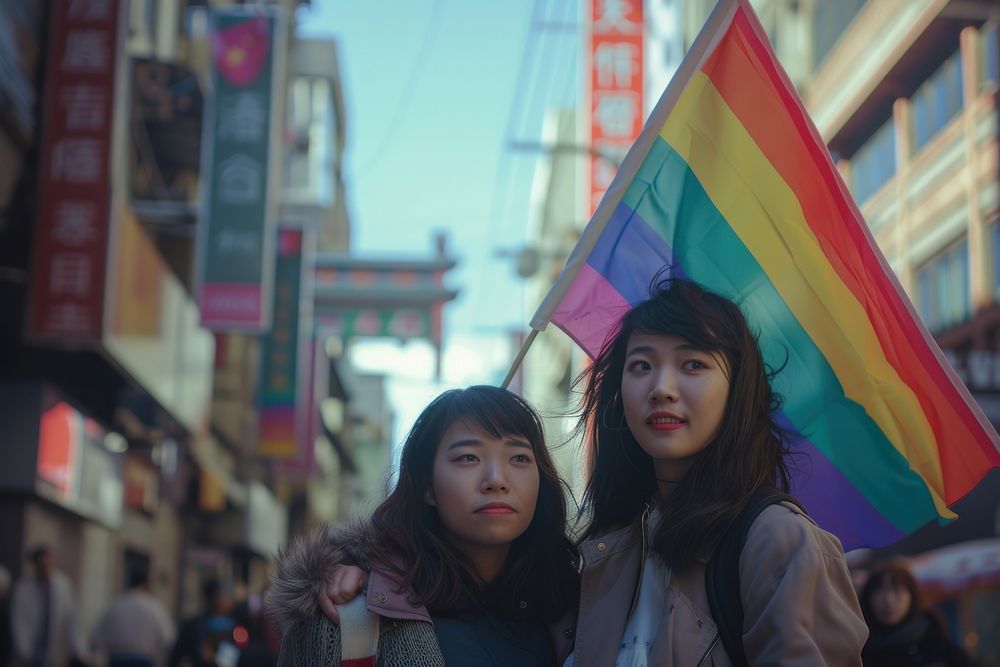 Couple asian lesbian woman with gay pride flag on the street togetherness architecture celebration.