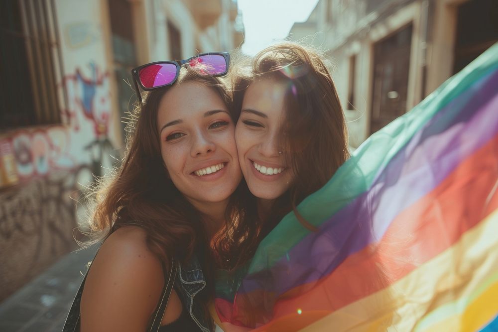 Couple lesbian woman with gay pride flag on the street photography portrait smile.