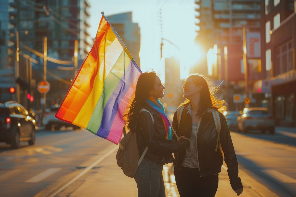 Couple lesbian woman with gay pride flag on the street adult togetherness architecture.
