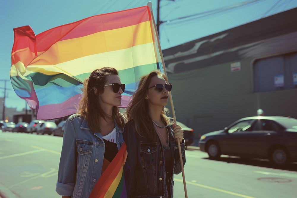 Couple lesbian woman with gay pride flag on the street glasses transportation togetherness.