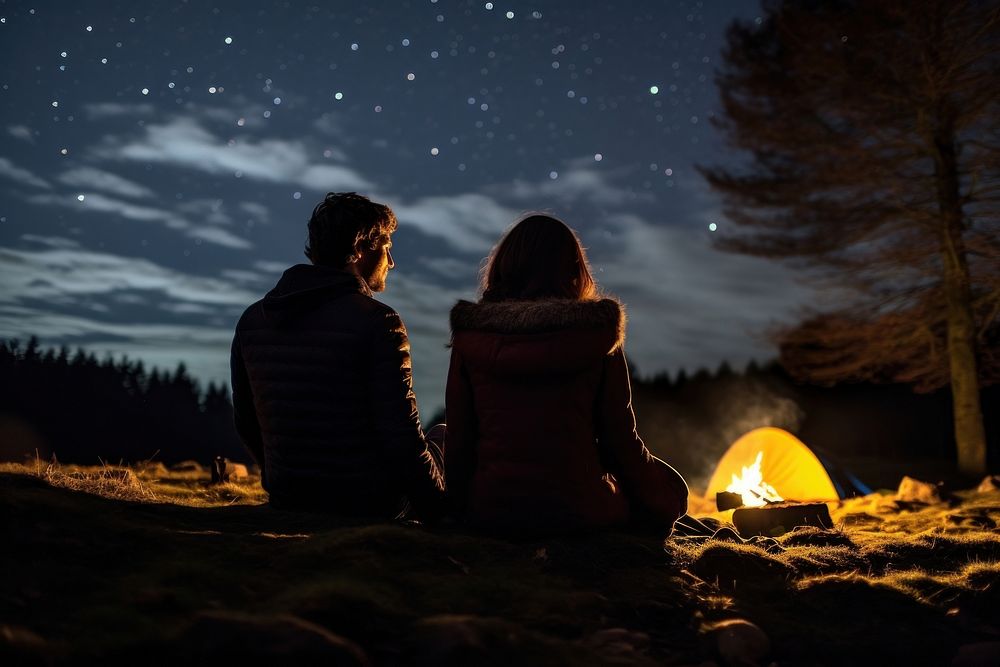 Young couple camping in autumn night fire outdoors.