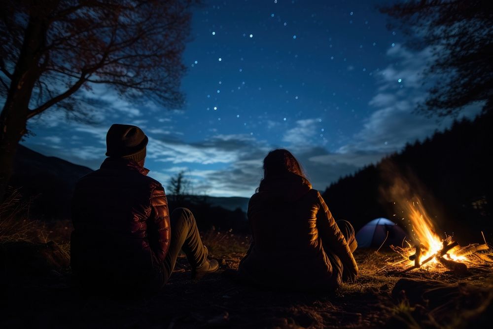 Young couple camping in autumn night outdoors bonfire.