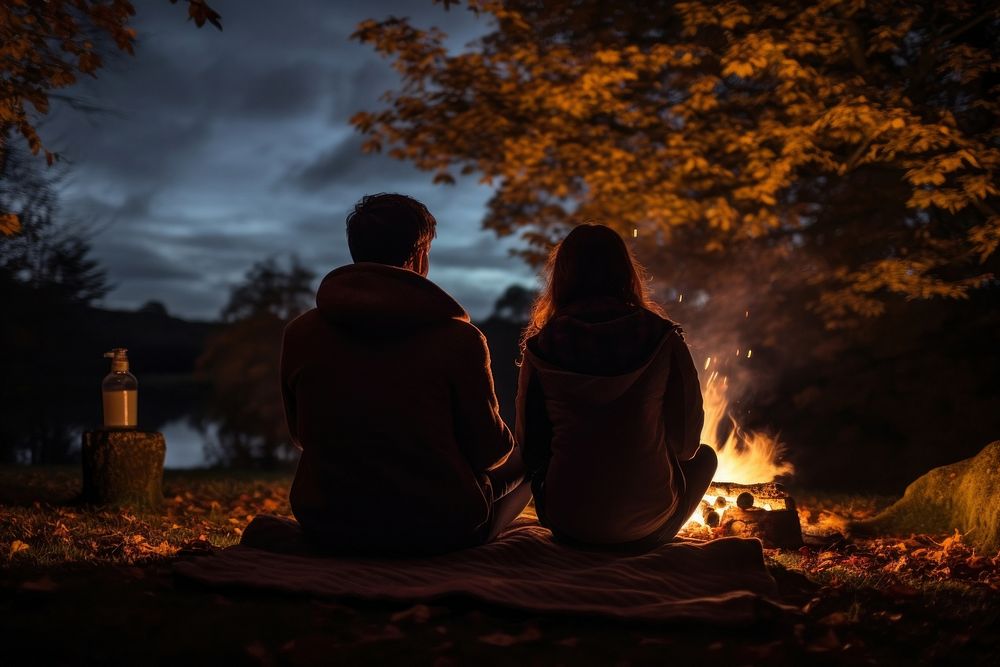 Young couple camping in autumn fire bonfire night.