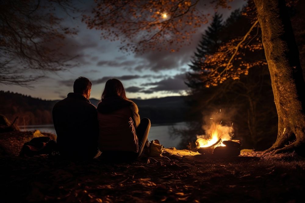 Young couple camping in autumn fire outdoors bonfire.