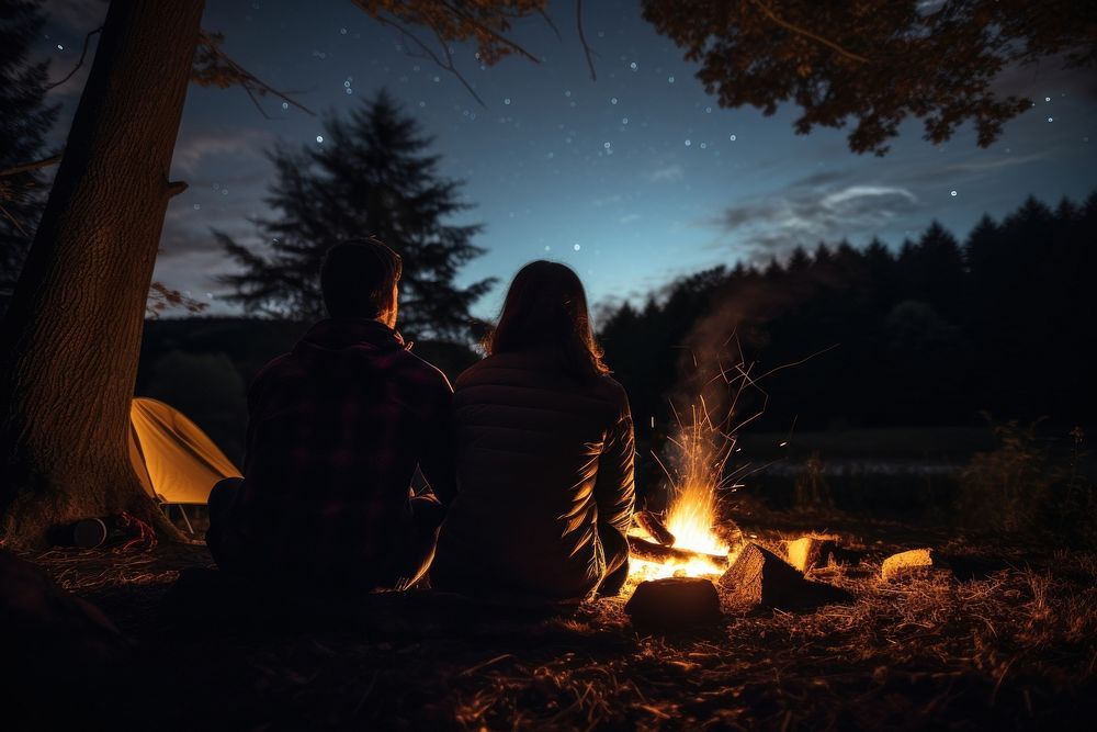 Young couple camping in autumn night fire outdoors.