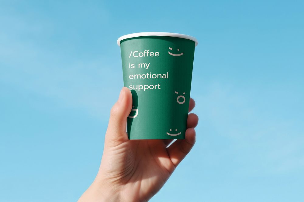Hand holding green disposable coffee cup