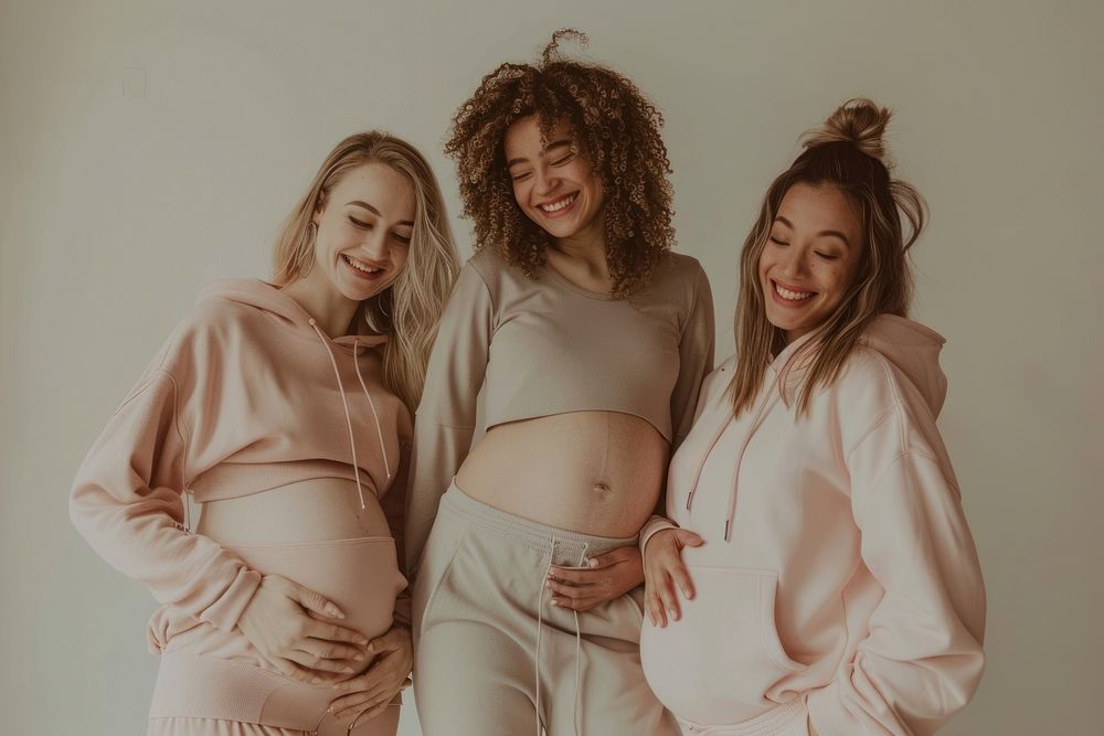 3 happy pregnant diverse women having a photoshoot for sport outfit laughing adult togetherness.