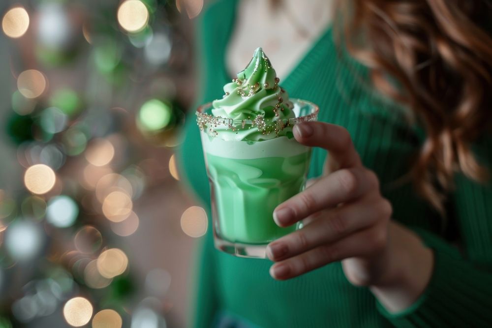 Woman drink green jello whip cream on top in a shot glass dessert food refreshment.