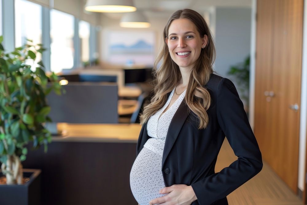 Happy pregnant woman in business suit standing in an office smile anticipation beginnings.