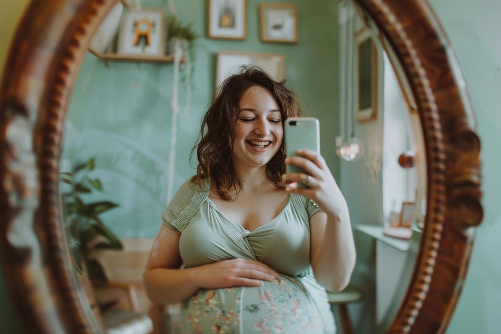 Happy pregnant woman talking a selfie in a mirror adult photo photographing.