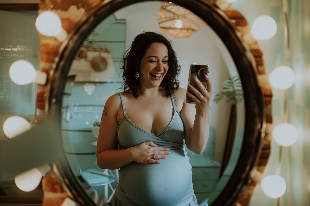 Happy pregnant woman talking a selfie in a mirror adult photo photographing.