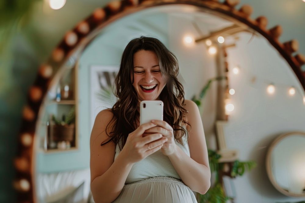 Happy pregnant woman talking a selfie in a mirror laughing adult photo.