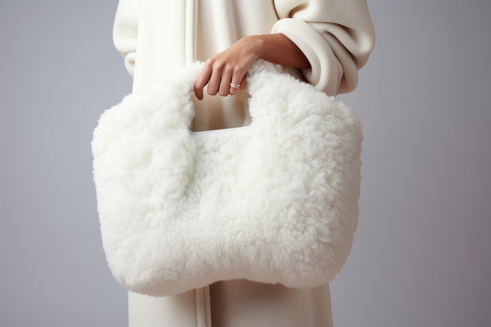 Woman carrying white textured faux-shearling bag handbag accessories midsection.