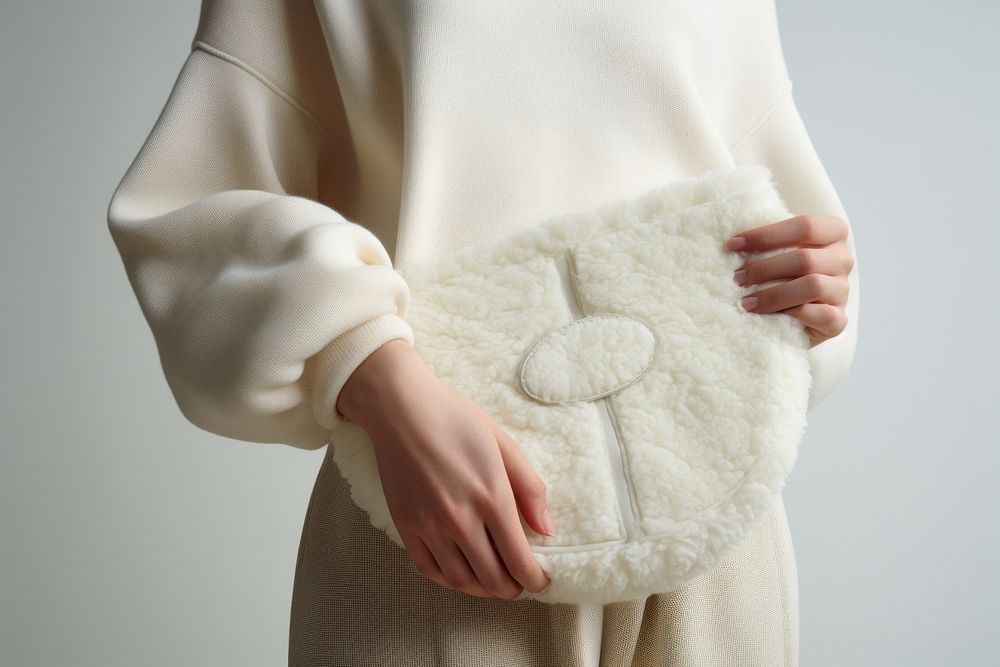 Woman carrying white textured faux-shearling bag accessories midsection outerwear.