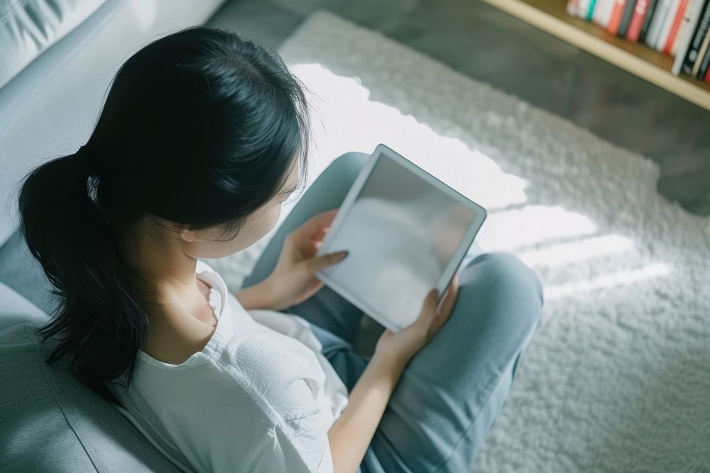 Woman using a tablet in the living room computer reading adult.