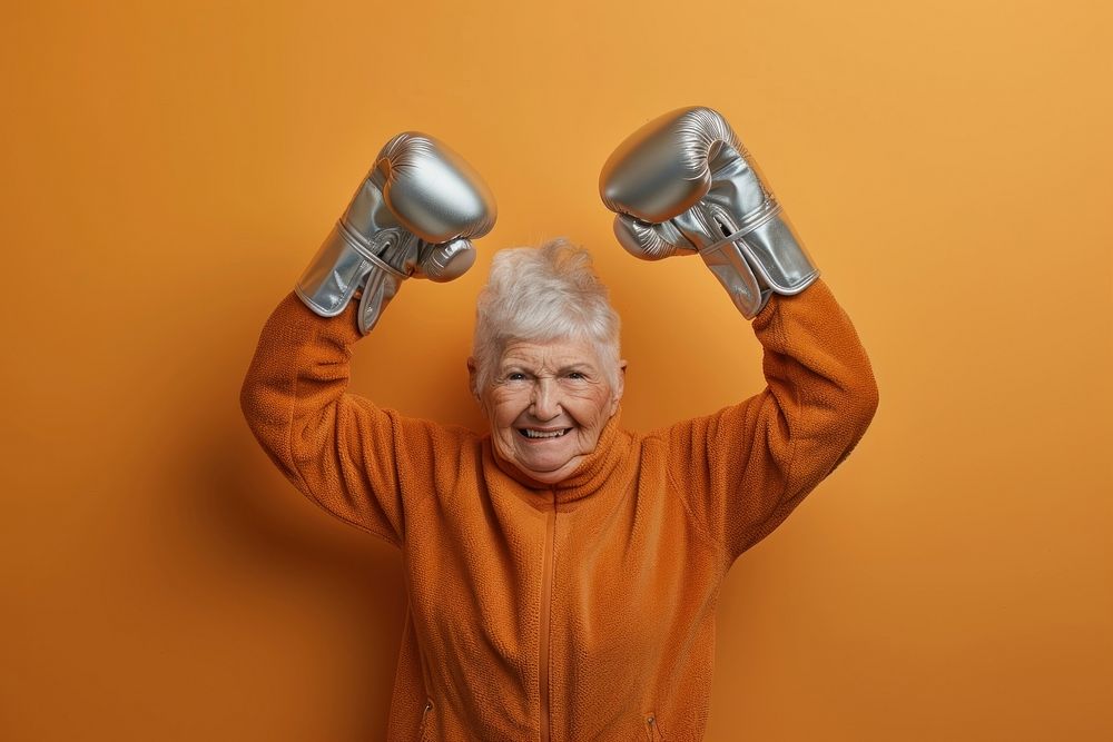 Female in activewear raising hands in silver shining boxing gloves cheerful adult retirement.
