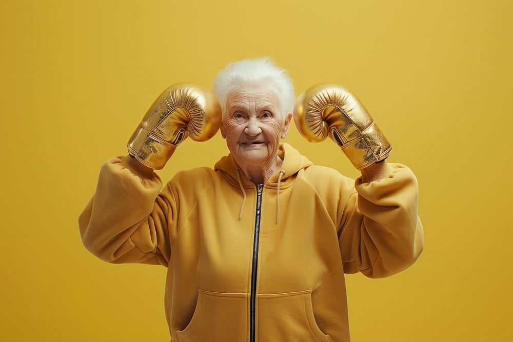 Female in activewear raising hands in golden shining boxing gloves adult retirement portrait.