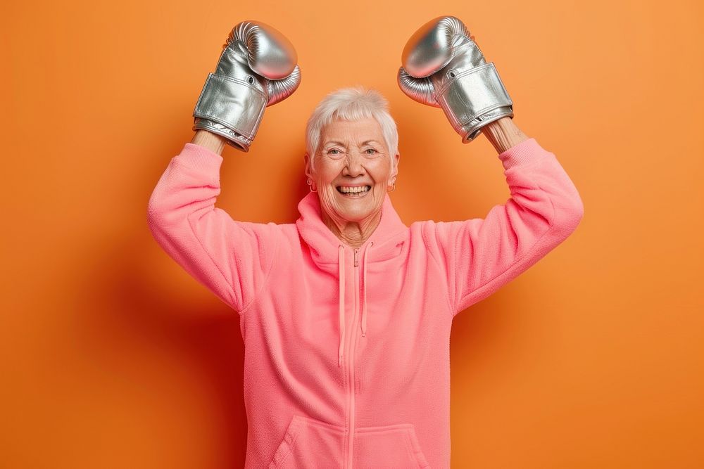 Female in activewear raising hands in silver shining boxing gloves cheerful adult retirement.