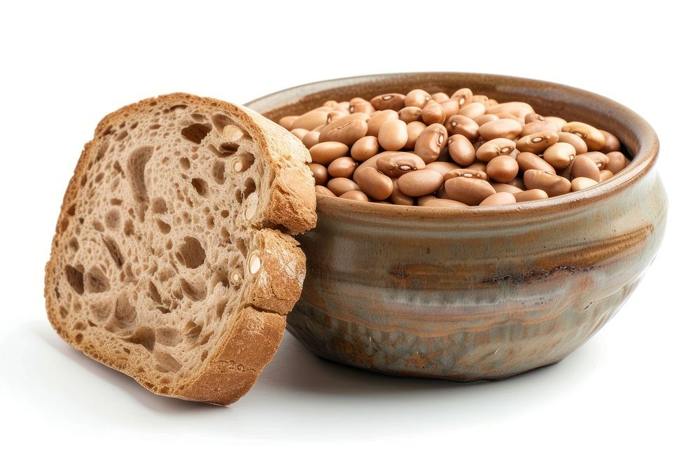 A bowl of pinto beans is paired with a slice of bread food white background breakfast.