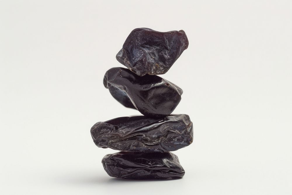 A stack of pitted prunes white background sculpture zen-like.
